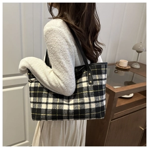 Detail of checkered tote bag showing thick wool fabric and leather straps with metal rivets