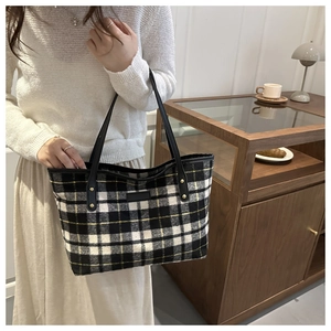 Detail of checkered tote bag with yellow accents and leather straps in a cozy setting