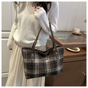 Detail of vintage plaid tote bag with brown leather straps and gold rivet accents