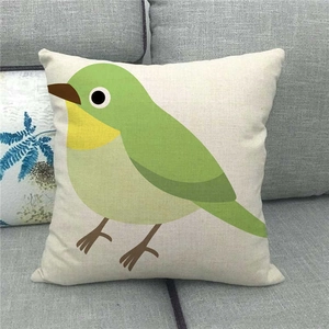 Détail d'une housse de coussin en lin avec motif oiseau vert sur un canapé gris