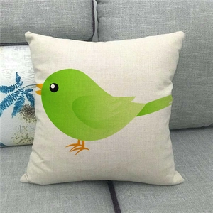 Gros plan d'une housse de coussin en lin avec un oiseau vert sur un canapé gris