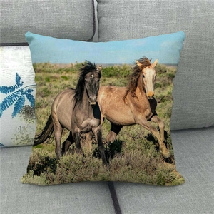 Linen cushion cover with wild horses running on African savanna displayed on sofa