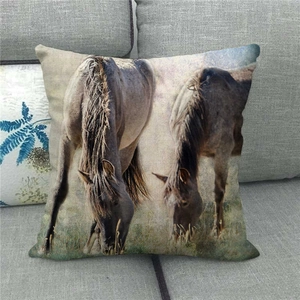Detailed close-up of a linen pillowcase featuring horses grazing on a grey sofa