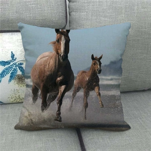 Linen cushion cover featuring wild horses running on African savannah, placed on a sofa