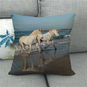 Detailed view of linen cushion cover with white horses running on a beach print