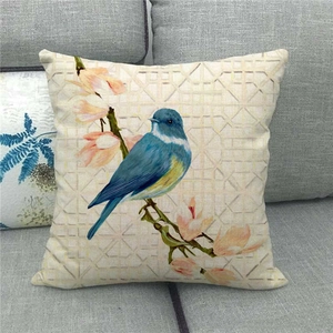Close-up of bird and flower watercolor print on textured linen cushion cover on a sofa