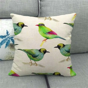 Detail of linen pillowcase with colorful watercolor birds resting on a sofa