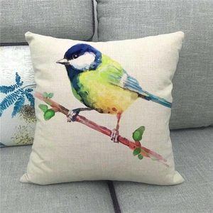 Detail of linen cushion cover showing vibrant watercolor bird on a gray fabric sofa