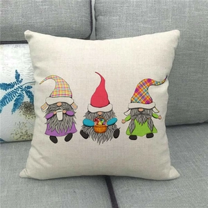 Detailed view of linen pillow cover with festive gnomes on a gray fabric sofa