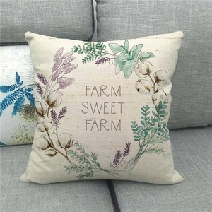 Detail of linen pillow cover with Farm Sweet Farm floral wreath on a grey fabric sofa