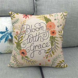Detail of floral linen pillow cover with Bloom with Grace text on gray sofa