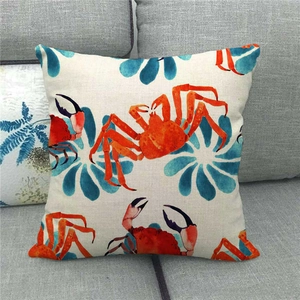 Linen pillowcase with red watercolor crab and blue floral print on a gray sofa