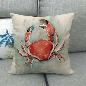 Close-up of linen pillow cover with red watercolor crab print on a gray fabric sofa