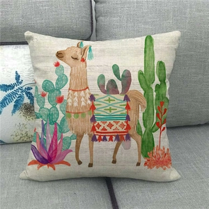 Close-up of linen cushion cover with colorful llama and cactus embroidery on a gray sofa