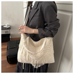 Detail of cream macrame tote bag featuring handcrafted crochet texture and long fringe