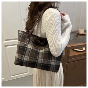 Close-up of retro plaid tote bag showing dark brown leather straps and rivet detail