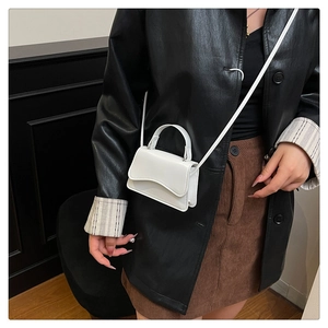 Close-up of white mini square bag with wave-edge flap worn with a black leather jacket