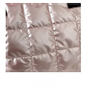 Macro shot of high-quality quilted fabric with metallic pink gloss and soft square texture