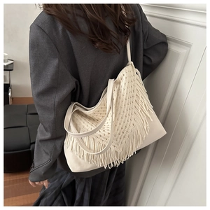 Detail view of large beige tote bag with fringe tassels and woven crochet texture