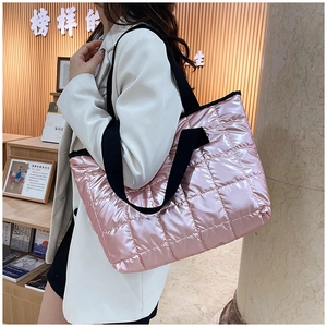 Close-up of pink quilted puffer tote bag with black strap in a cozy bookstore setting