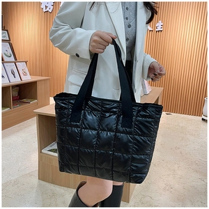 Close-up of black quilted puffer tote bag featuring durable nylon fabric and square stitching