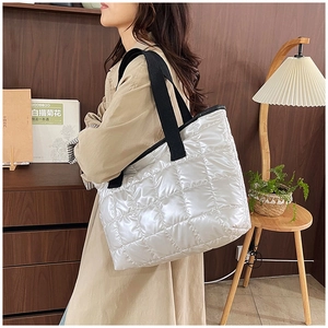 Lifestyle view of a large white quilted puffer tote bag with black strap handles