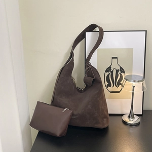 Grand sac cabas marron foncé en cuir mat avec pochette assortie dans un décor minimaliste