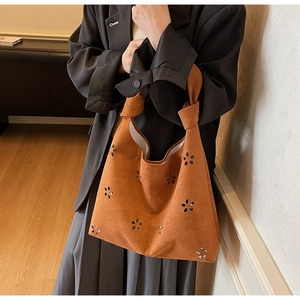 Détail de fleurs découpées au laser sur sac cabas en daim marron avec bandoulière nouée