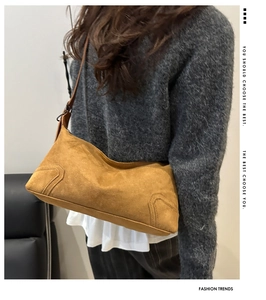 Detail view of the wave-shaped opening and reinforced corners on the brown suede shoulder bag