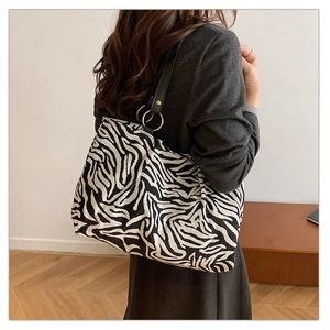 Detail shot of a zebra print tote bag with black leather strap and gold hardware accents
