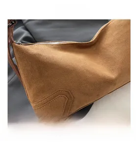 Detail of brown faux suede shoulder bag featuring matte texture and silver metal zipper