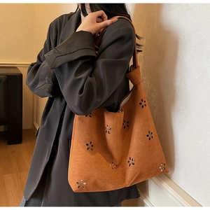 Détail du motif floral découpé au laser sur le sac cabas en daim orange de luxe