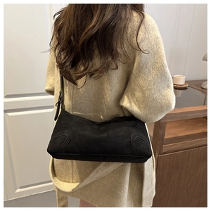 Rear view of model wearing a black matte suede shoulder bag with curved stitching details