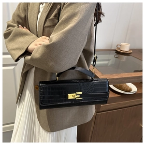 Detailed view of black crocodile pattern crossbody bag with elegant gold hardware