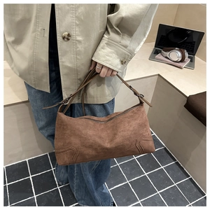 Close-up of brown matte suede shoulder bag with decorative stitching and metal zipper detail