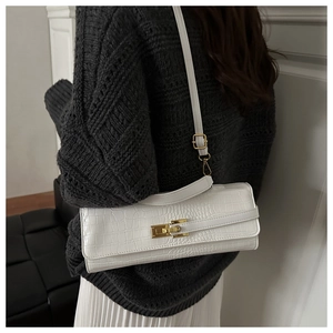 Detail of white crocodile texture handbag with golden lock worn by a fashion model