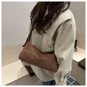 Detail of vintage brown suede hobo bag with curved stitching and adjustable strap