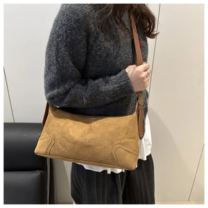 Detail view of tan suede shoulder bag with vintage curved stitching and long strap