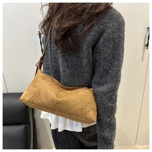 Detailed close-up of brown suede shoulder bag with vintage texture and stitching