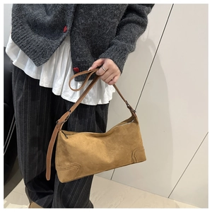 Detail of matte suede texture on camel shoulder bag with smooth zipper closure