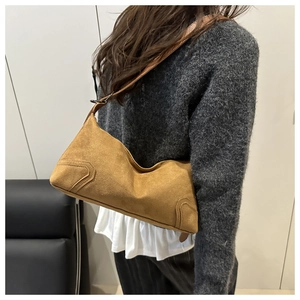 Detailed view of brown suede underarm bag with unique curved design and reinforced stitching
