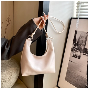 Detail of lychee textured cream hobo bag featuring a unique knotted strap and metal ring