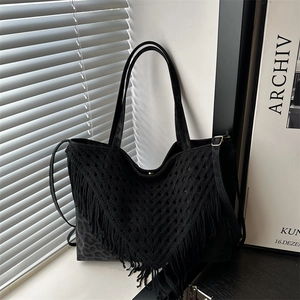 Black large tote bag with V-shaped fringe and leopard pattern under natural window light