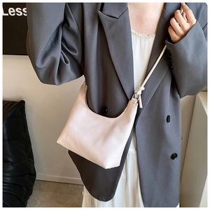 Detail of light beige crescent bag with textured leather and unique knotted shoulder strap