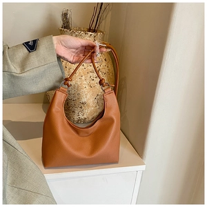 Detail of a brown crescent hobo bag showing the knotted strap and metallic ring attachment