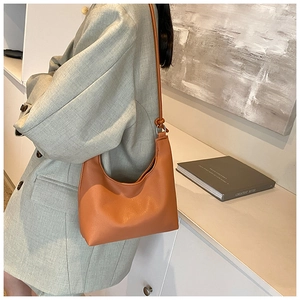 Detail of ginger orange textured leather hobo bag showing shoulder strap and draping effect