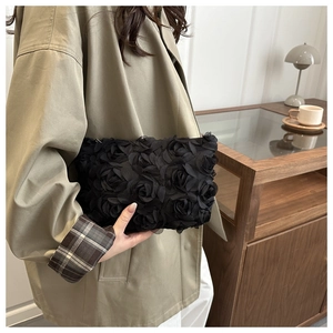 Close-up of elegant black 3D rose petal handbag with textured chiffon floral details