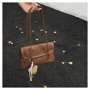 Detail of suede shoulder bag with woven rope trim and cute bear charm pendant