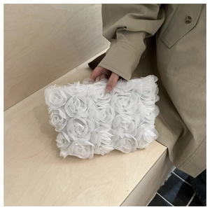 Detailed close-up of 3D lace floral patterns and delicate mesh texture on white clutch