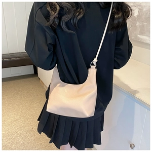 Detail of creamy white crescent bag showing pebbled leather texture and knotted strap design